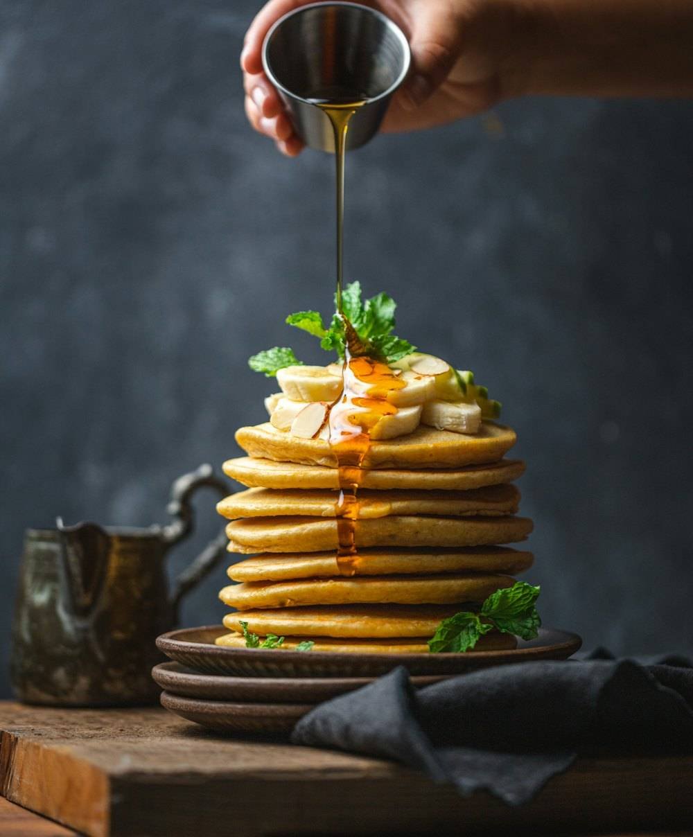 Stack of buttermilk pancakes with honey being poured over