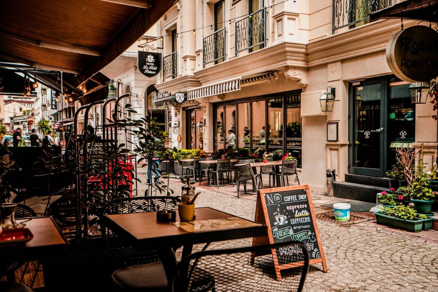 Outdoor terrace seating with small tables under leafy trees